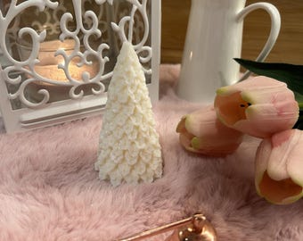 May include: A cream-colored, cone-shaped candle with a textured, leaf-like surface. The candle is accompanied by a white metal lantern, a white ceramic pitcher, two pale pink tulip flowers, and a rose gold-toned metal candle snuffer.