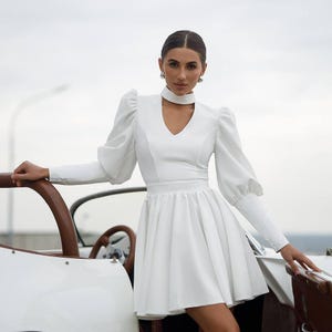 Vestido de novia corto blanco de manga larga con mangas abullonadas llamativas y falda acampanada: perfecto para ocasiones especiales.