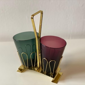 Könnte beinhalten: Ein goldfarbener Metallständer mit zwei gläsernen Bechern. Die Becher sind türkis und lila.