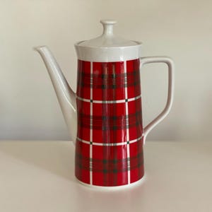 Könnte beinhalten: Weiße Kaffeekanne aus Keramik mit rotem und schwarzem Karomuster.