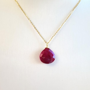 May include: A gold chain necklace with a teardrop-shaped ruby pendant.