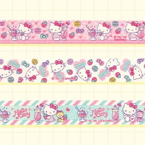 May include: Three rolls of pink, white, and blue patterned washi tape featuring Hello Kitty and a strawberry and ice cream theme. The text on the tape reads "Hello Kitty".