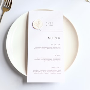 Eleganckie menu weselne z białą pieczęcią lakową i etykietą z imieniem – klasyczne nakrycie stołu weselnego – minimalistyczne spersonalizowane menu – dekoracja stołu weselnego