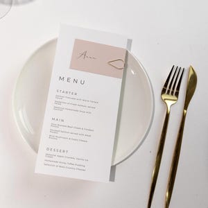 Modern trouwmenu met blozende couvert – gouden druppelvormige clip menukaart – roze tafeldecor – minimale bruiloft briefpapier
