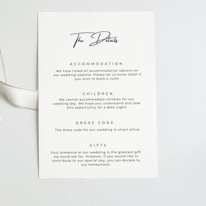 Puede incluir: Una tarjeta de informaci&oacute;n de boda rectangular blanca con texto en negro titulada The Details. Enumera secciones para alojamiento, ni&ntilde;os, c&oacute;digo de vestimenta y regalos. Una cinta gris claro est&aacute; unida al lado izquierdo de la tarjeta.