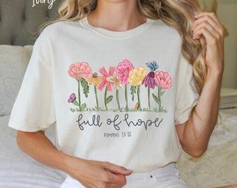 May include: Ivory t-shirt featuring a floral design and the text "full of hope" with the scripture reference "Romans 15:13".