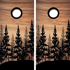 May include: Two wooden cornhole boards with a silhouette of a forest and a full moon at sunset. The boards are brown with a wood grain pattern.