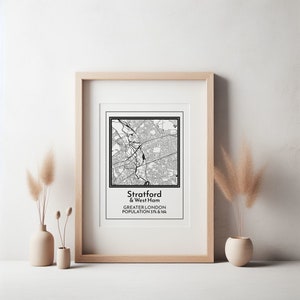 Puede incluir: Impresión enmarcada en blanco y negro del mapa de Stratford & West Ham, Gran Londres, con una población de 37k y 16k. La impresión está en un marco de madera clara, con un passe-partout blanco. Jarrones decorativos con plantas secas en primer plano.
