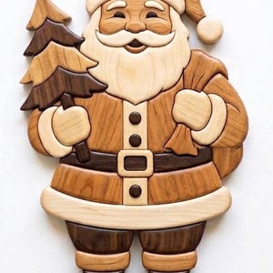 Puede incluir: Una decoración de pared de madera hecha a mano que representa a Santa Claus, ensamblada con diferentes tonos de madera clara y oscura. La figura incluye un gorro, una barba larga, un cinturón con hebilla, botas y un saco, sosteniendo un árbol.