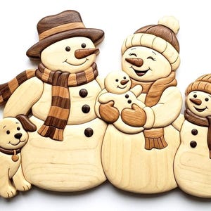 May include: A wooden wall art piece featuring a family of three snowmen and a dog. The snowmen wear hats and striped scarves in shades of brown and tan. One snowman holds a small baby snowman. A light brown dog sits beside them.