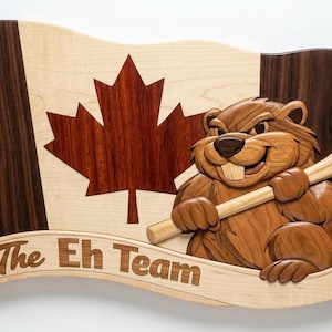 May include: Wooden wall art featuring a waving Canadian flag with a maple leaf and a smiling beaver holding a hockey stick. The banner below reads "The Eh Team". The art is made of various wood tones.