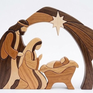 May include: A wooden nativity scene featuring figures of a standing adult, a kneeling adult, and an infant in a manger, all crafted from various shades of light and dark wood. An arched structure with a star is positioned above the figures.