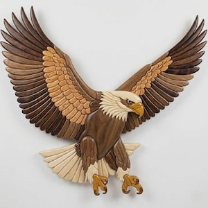 May include: A wooden wall art piece depicting a bald eagle in flight. The eagle's wings are spread wide, showcasing a detailed pattern of brown, tan, and cream-colored wood. The eagle's head is white with a yellow beak and brown eyes.