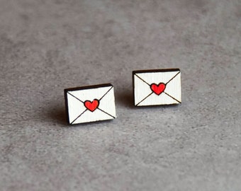 May include: A pair of wooden earrings shaped like envelopes with a red heart on the front.