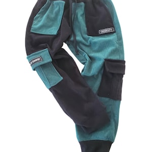 May include: Corduroy pants in teal and black with multiple pockets and a drawstring waist. The pants have the text "R Gnarly" on the cuff and "OHZIGGY" on a patch. The pants are made of a soft corduroy material.