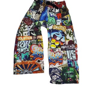 Peut inclure: Pantalon coloré avec un motif de style graffiti. Le pantalon présente diverses images et textes, dont les mots "Evolution in Pro" et "Peace Mtn". Il possède une taille élastique.