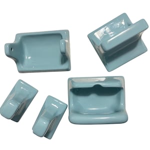 Peut inclure: Ensemble de cinq accessoires de salle de bain en céramique bleu clair. L'ensemble comprend un porte-savon, un porte-papier toilette et plusieurs crochets à serviettes. Les accessoires ont une finition brillante et un design classique et vintage.