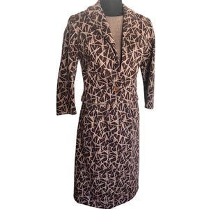 May include: A two-piece brown and beige patterned suit. The blazer has a single button closure and long sleeves. The skirt is knee-length. The suit is displayed on a mannequin.