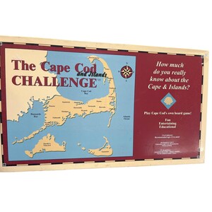May include: A board game titled "The Cape Cod Challenge" with a map of Cape Cod and surrounding islands. The game box features a maroon background with text asking, "How much do you really know about the Cape & Islands?"