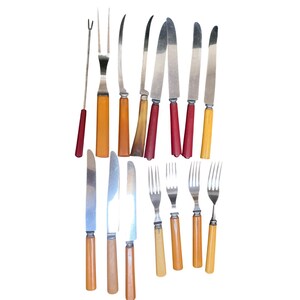 Könnte beinhalten: Eine Sammlung von Vintage-Besteck mit verschiedenen Metallmessern, Gabeln und Servierutensilien mit unterschiedlichen Griffen in Rot-, Orange-, Gelb- und Brauntönen. Das Set enthält eine zweizinkige Gabel, mehrere Messer und vier Gabeln.