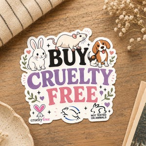 May include: A sticker with the words "BUY CRUELTY FREE" in purple and pink, featuring illustrations of a rabbit, a rat, and a dog. The sticker also includes the text "cruelty free" and "NOT TESTED ON ANIMALS".