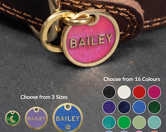 May include: A dark brown leather collar with a gold-toned metal ring holding a circular pink glitter pet tag engraved with the name BAILEY. The image displays options for 3 sizes: 20mm, 25mm, and 30mm, along with a chart of 16 color choices.