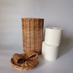 Natural color wicker toilet paper basket next to two stacked rolls, showing its internal capacity. Compact and charming storage
