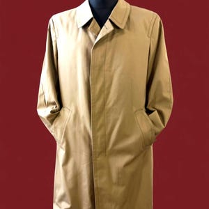 May include: A tan trench coat with a classic design, displayed on a black mannequin. The coat features a collared neckline, long sleeves, and two front pockets. The coat is made of a smooth, lightweight fabric.