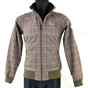 May include: A brown and tan plaid jacket with a zipper closure and a Bergans logo on the left chest. The jacket has a ribbed collar and cuffs.