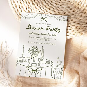 May include: A white invitation card with green text and illustrations. The card reads "Dinner Party" and includes details such as the date, time, and RSVP information. The design features a table setting, floral arrangements, and string lights.