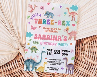 May include: A pink and blue birthday invitation with a dinosaur theme. The invitation says "She's a Three-Rex" and "Sabrina's 3rd Birthday Party". The invitation also includes the date and time of the party, as well as the address and RSVP information.