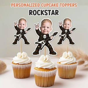 May include: Three cupcakes topped with white frosting and personalized "Rockstar" cupcake toppers. The toppers feature a cartoon image of a child in a black leather jacket, holding a guitar and making a rock and roll hand gesture. The text "PERSONALIZED CUPCAKE TOPPERS" is at the top.
