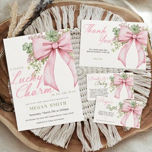 May include: Baby shower invitation set with a pink bow and shamrock design. The set includes an invitation, thank you card, and two smaller cards. The invitation reads "A Little Lucky Charm Is On The Way!" in pink script.