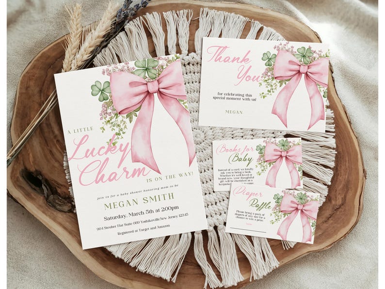 May include: Baby shower invitation set with a pink bow and shamrock design. The set includes an invitation, thank you card, and two smaller cards. The invitation reads "A Little Lucky Charm Is On The Way!" in pink script.