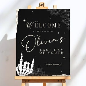May include: Black and white welcome sign with the text "Welcome, We are mourning Olivia's Last Day of Youth, XIII - IX - MMXXV". The sign features a skeleton hand giving the middle finger and floral designs.