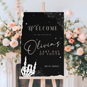May include: Black and white welcome sign with the text "Welcome, We are mourning Olivia's Last Day of Youth, XIII - IX - MMXXV". The sign has a skeleton hand with a middle finger up and floral designs.