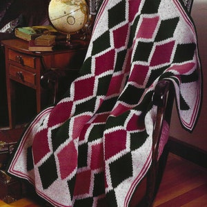 May include: A crocheted diamond patterned throw blanket in burgundy, black, and white. The blanket is draped over a wooden armchair.