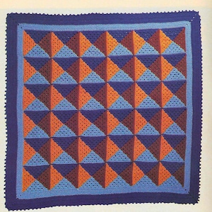 Puede incluir: Una manta de ganchillo con un patrón geométrico de triángulos azules y naranjas. La manta tiene un borde morado.