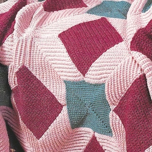 Könnte beinhalten: Eine gehäkelte Decke mit einem geometrischen Muster in den Farben Rosa, Burgunderrot und Türkis.