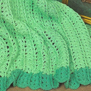 May include: A green crocheted blanket with a scalloped edge. The blanket is made with a light green and a darker green yarn.