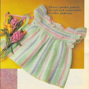 May include: A crocheted baby dress with pastel stripes in pink, green, blue, and white. The dress has a ruffled neckline and short sleeves. The text "Flower garden pastels in soft and comfortable crochet fashions." is printed above the dress.