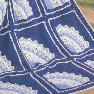 May include: A crocheted blanket with a blue and white pattern. The blanket is made up of squares with a scalloped design in the center.