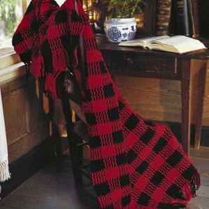 May include: A red and black crocheted throw blanket with fringe, draped over a wooden chair. The blanket has a checkered pattern.