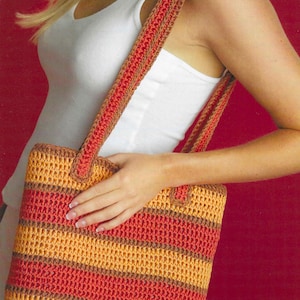 May include: A handmade crochet tote bag with a striped pattern in shades of orange, red, and brown. The bag has a rectangular shape with matching crochet straps. The bag is designed for carrying items.