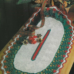 May include: White crochet table runner with a red center stripe and green and red trim. The runner is decorated with small red hearts and is shaped like a Christmas tree.