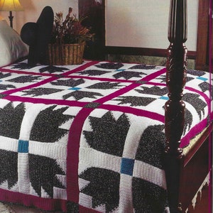 Pode incluir: Uma manta de crochê branca e preta com uma borda rosa. A manta está em uma cama com uma cabeceira de madeira e um poste de madeira.