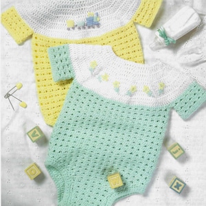 May include: Two handmade crochet baby rompers. One is yellow with a white collar and a train applique. The other is mint green with a white collar and flower appliques. A baby bottle and blocks are also in the image.