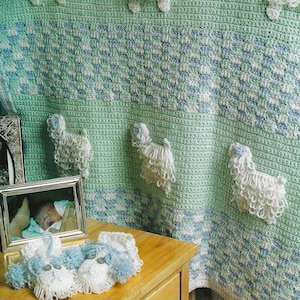 May include: A green crocheted baby blanket with a white and blue checkered pattern. The blanket features several crocheted white sheep appliques.