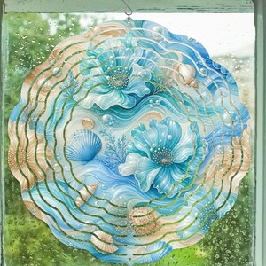 May include: A circular wind spinner featuring a coastal theme with blue and beige tones. The design displays stylized blue flowers, various seashells, and scattered pearls against a background of swirling waves and aquatic plant life.