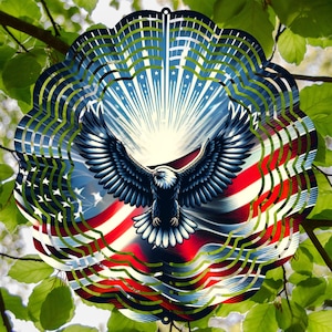 May include: A decorative metal wind spinner featuring an American flag design with a bald eagle. The patriotic artwork includes red and white stripes, blue with white stars, and a soaring eagle with outstretched wings. The spinner has a scalloped edge.